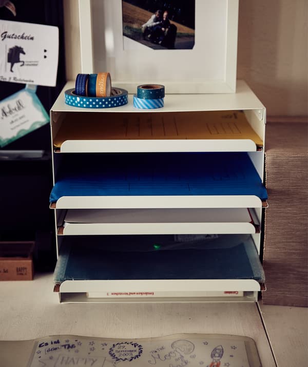Dossiers rangés dans une corbeille à courrier blanche.