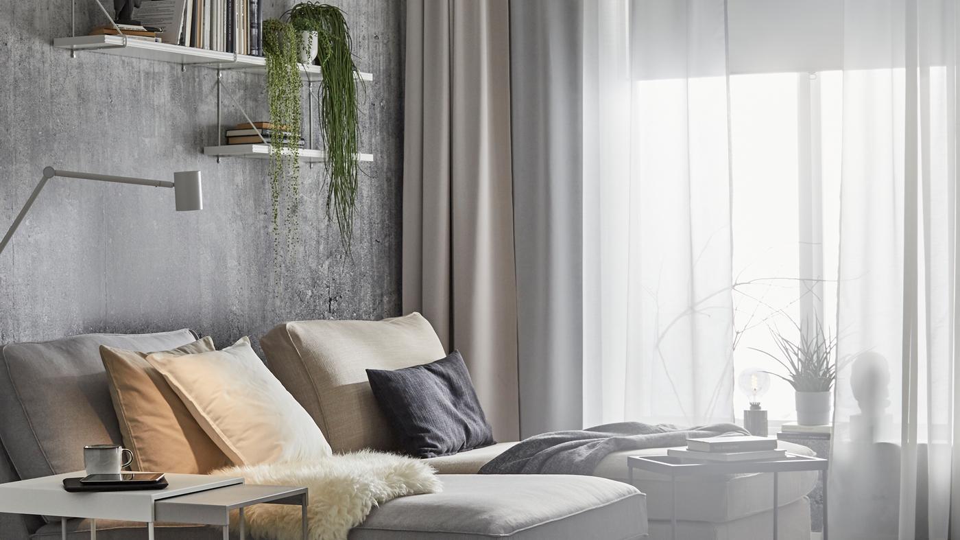 Două șezlonguri KIVIK lângă o fereastră mare, cu diferite perdele, inclusiv draperii opace HILLEBORG.