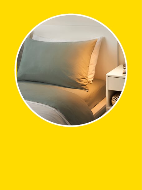 Draps et oreillers disposés en cercle sur fond jaune