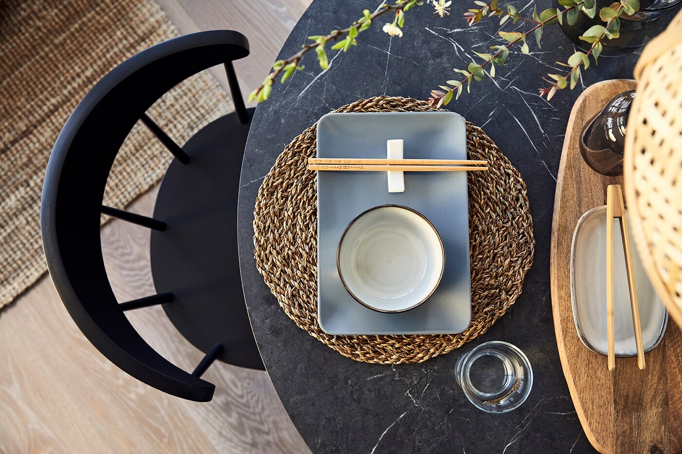 Draufsicht auf einen runden Tisch mit einem Tischset aus Seegras mit Teller, Schüssel und Ess-Stäbchen darauf