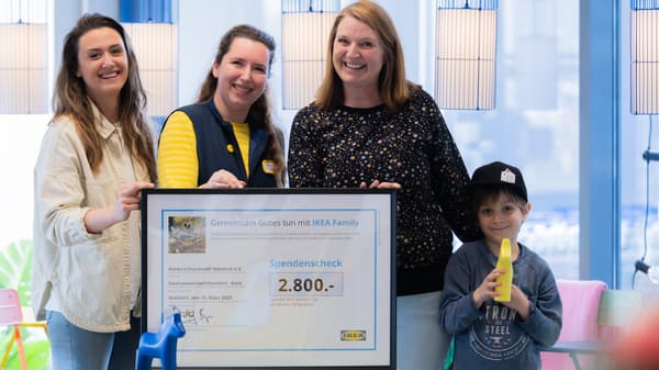 Drei Frauen und ein Kind stehen im IKEA Store und nehmen den Spendenscheck aus dem Malwettbewerb entgegen.