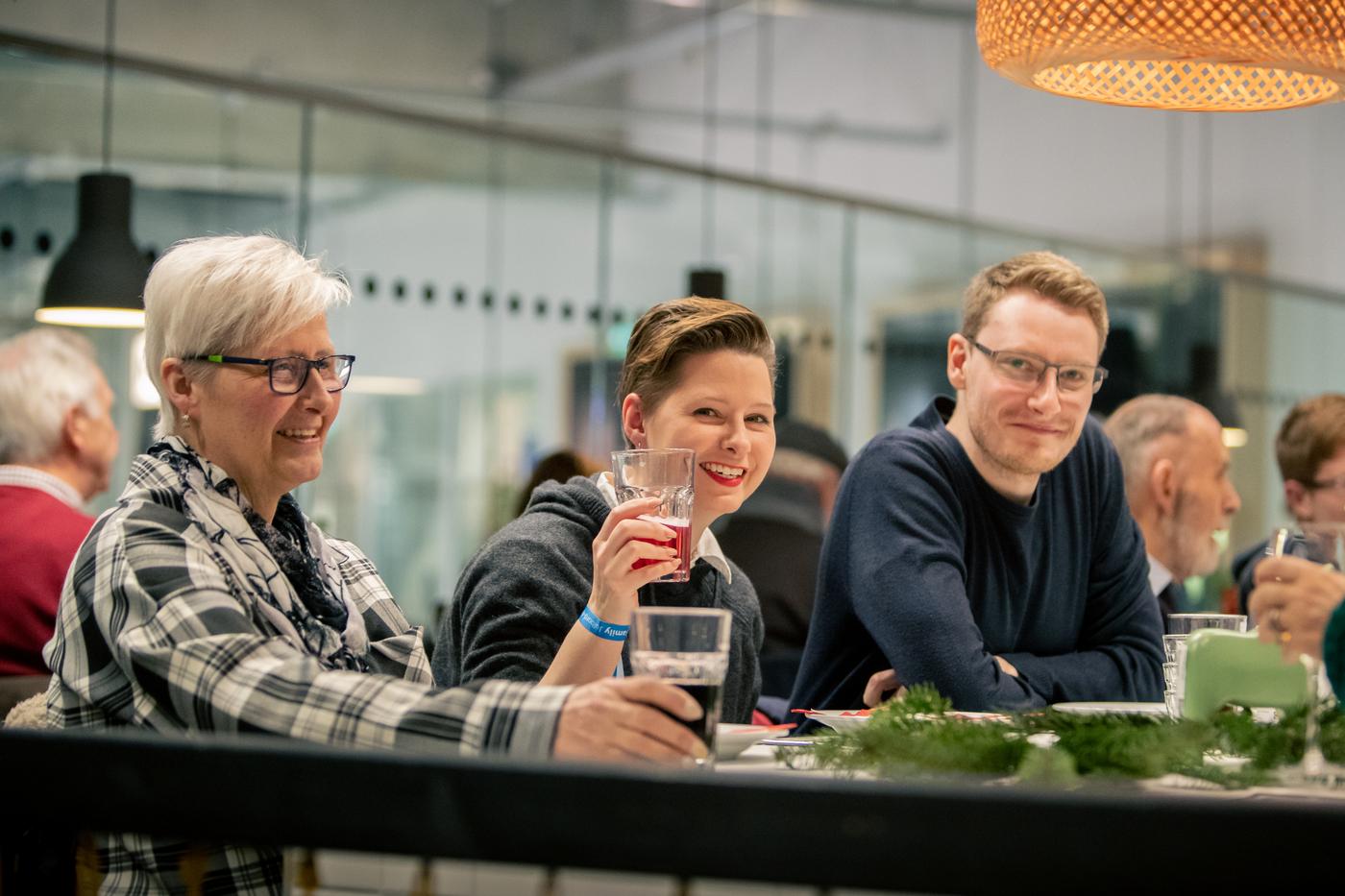 Drei Personen sitzen an einem Tisch und unterhalten sich.
