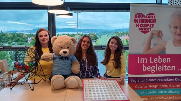 Drei Personen stehen gemeinsam an einem Bingo-Tisch im IKEA Einrichtungshaus Frankfurt Nieder-Eschbach. Zu sehen sind Mitarbeitende von IKEA, eine Mitarbeiterin der „Deutschen Kinderhospiz Dienste“, ein Bingo-Spiel sowie ein Informationsaufsteller der Organisation.