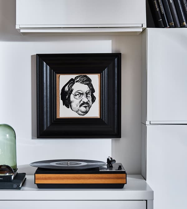 Drei TRONES Aufbewahrungen in Weiss bilden einen Augenfang in L-Form, der das Portrait in der Mitte optisch einrahmt.