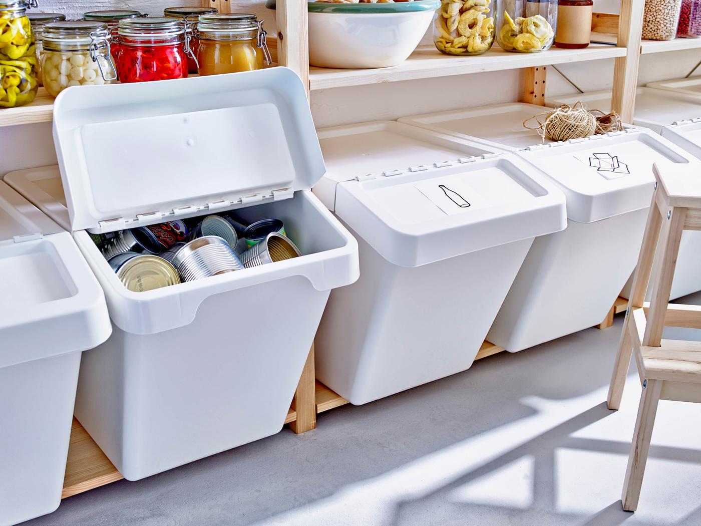 Drevené police plné bielych odpadkových košov SORTERA s vytriedeným odpadom.