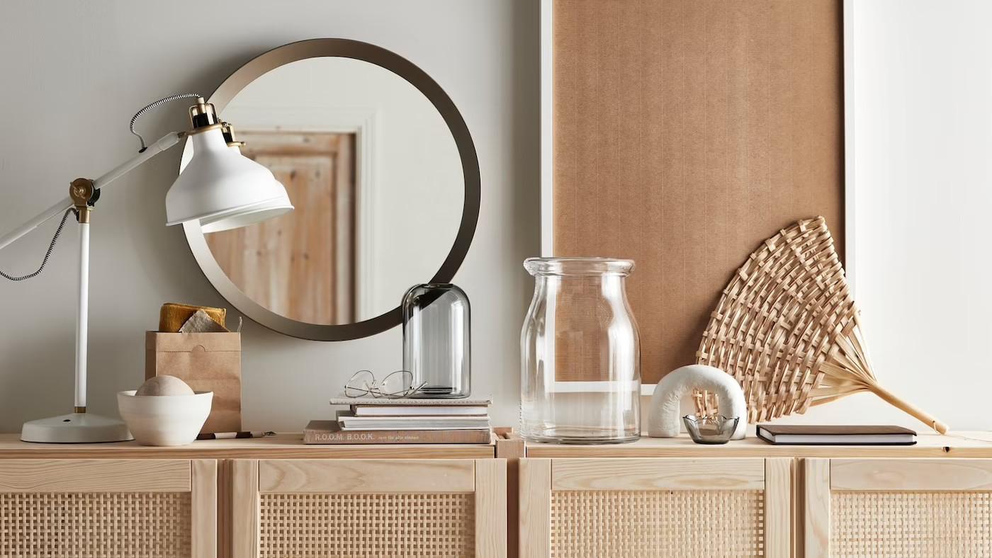 drewniana komoda z lampką, książkami i wazonem