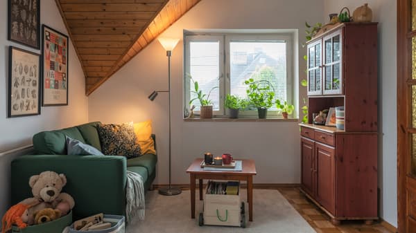 Drewniany wózek na zabawki FLISAT stojący pod stolikiem kawowym w jasnym pokoju dziennym.