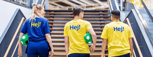 Drie IKEA medewerkers die de trap oplopen. Twee hebben een groene voetbal vast onder zijn armen