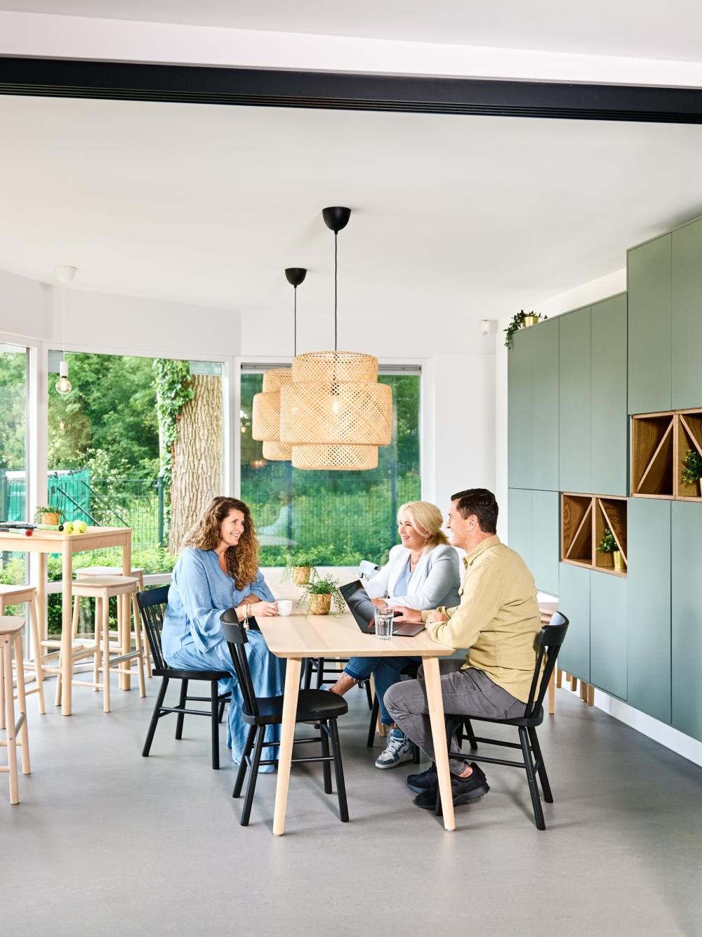 Drie personen die gezellig aan het praten zijn aan tafel