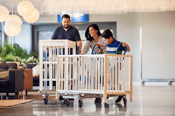 Družina pelje sestavljeno pohištvo IKEA po hodniku.