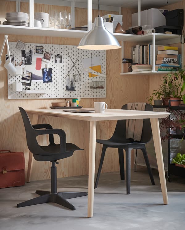 Drveni blagovaonski stol s dvije ODGER stolice boje antracita pokraj njega: jedna je obična stolica, a druga uredska s naslonima za ruke.