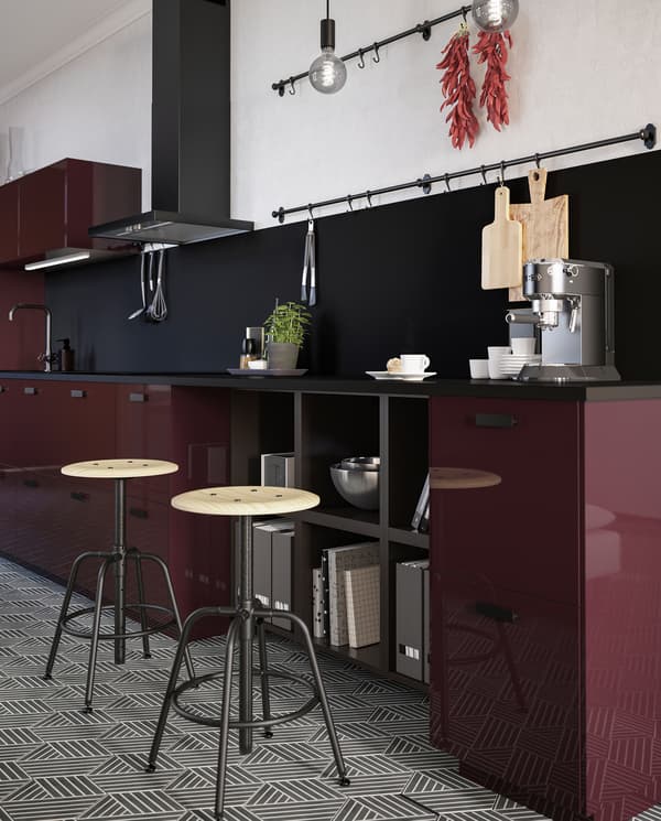 Dua bangku KULLABERG berwarna hitam/pain berada di sebelah permukaan atas kaunter dapur yang menempatkan alat pembuat kopi dan beberapa koleh berdekatan.
