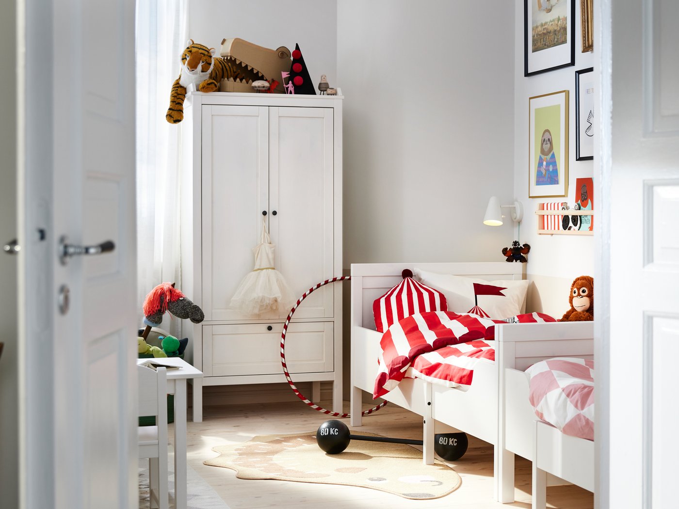 Dúas camas extensibles SUNDVIK brancas colocadas fronte a fronte contra a parede xunto a un armario SUNDVIK branco nun dormitorio.