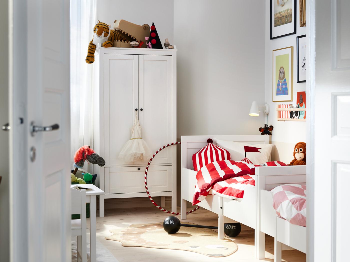 Duas camas extensíveis SUNDVIK em branco encostadas a uma parede junto a um roupeiro SUNDVIK em branco num quarto.