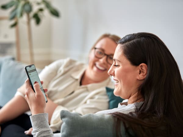 Duas mulheres sorriem ao olhar para o telemóvel