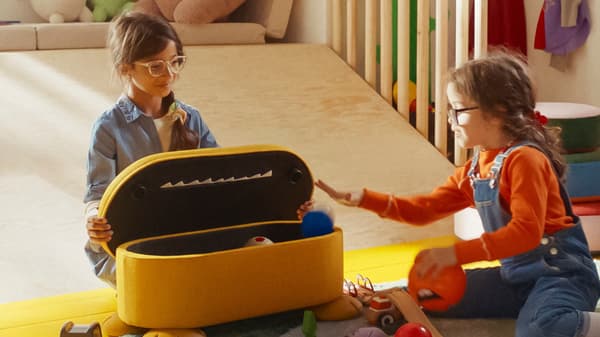 Due bambine mentre stanno giocando con un pouf con contenitore.