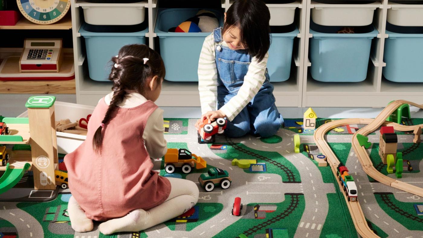 Due bambine stanno giocando su un tappeto con set e veicoli LILLABO.