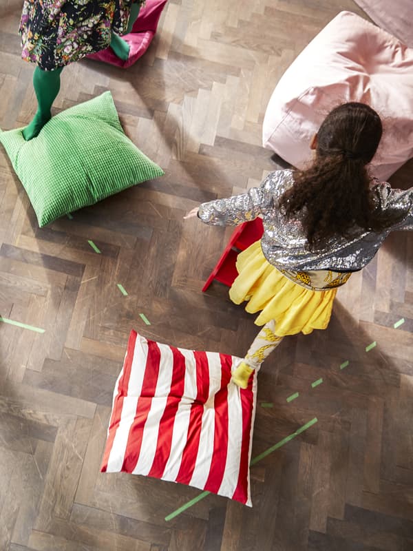 Due bambine viste dall'alto mentre stanno facendo un percorso di equilibrio su cuscini colorati.