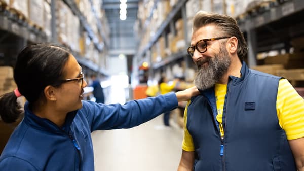 Due co-worker si stanno parlando all'interno di un negozio tra gli scaffali.