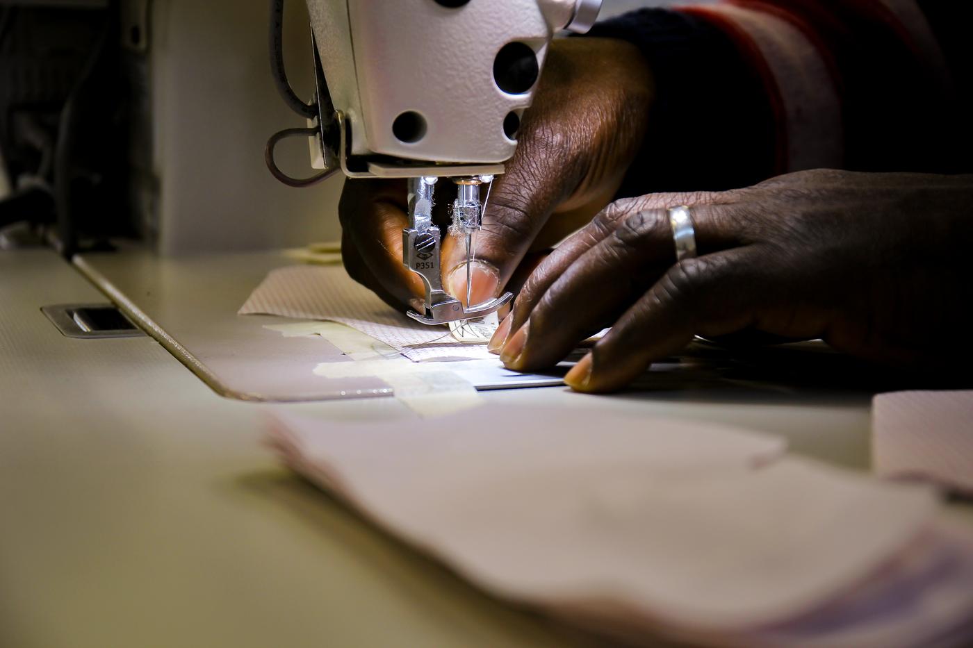 Due mani che usano la macchina da cucire.