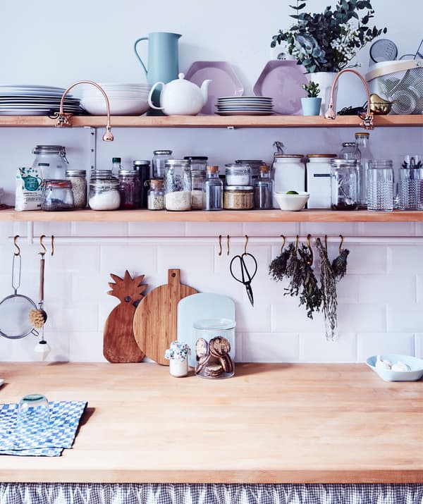Due mensole e un piano di lavoro in legno in cui sono organizzati stoviglie, spezie e utensili.