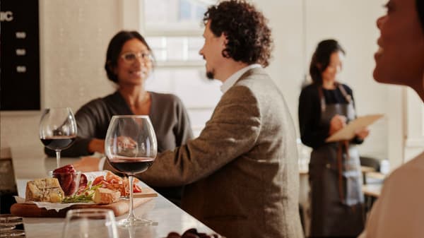 Due persone a un bancone parlano mentre fanno un aperitivo