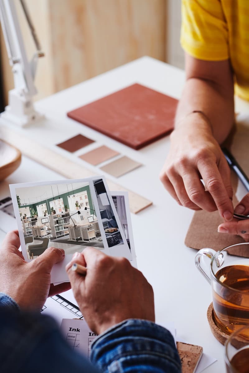 Due persone che progettano una stanza con foto e palette colori alla mano.