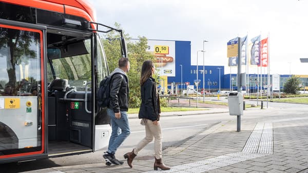 Due persone che scendono da un autobus e camminano verso l'ingresso di un negozio IKEA