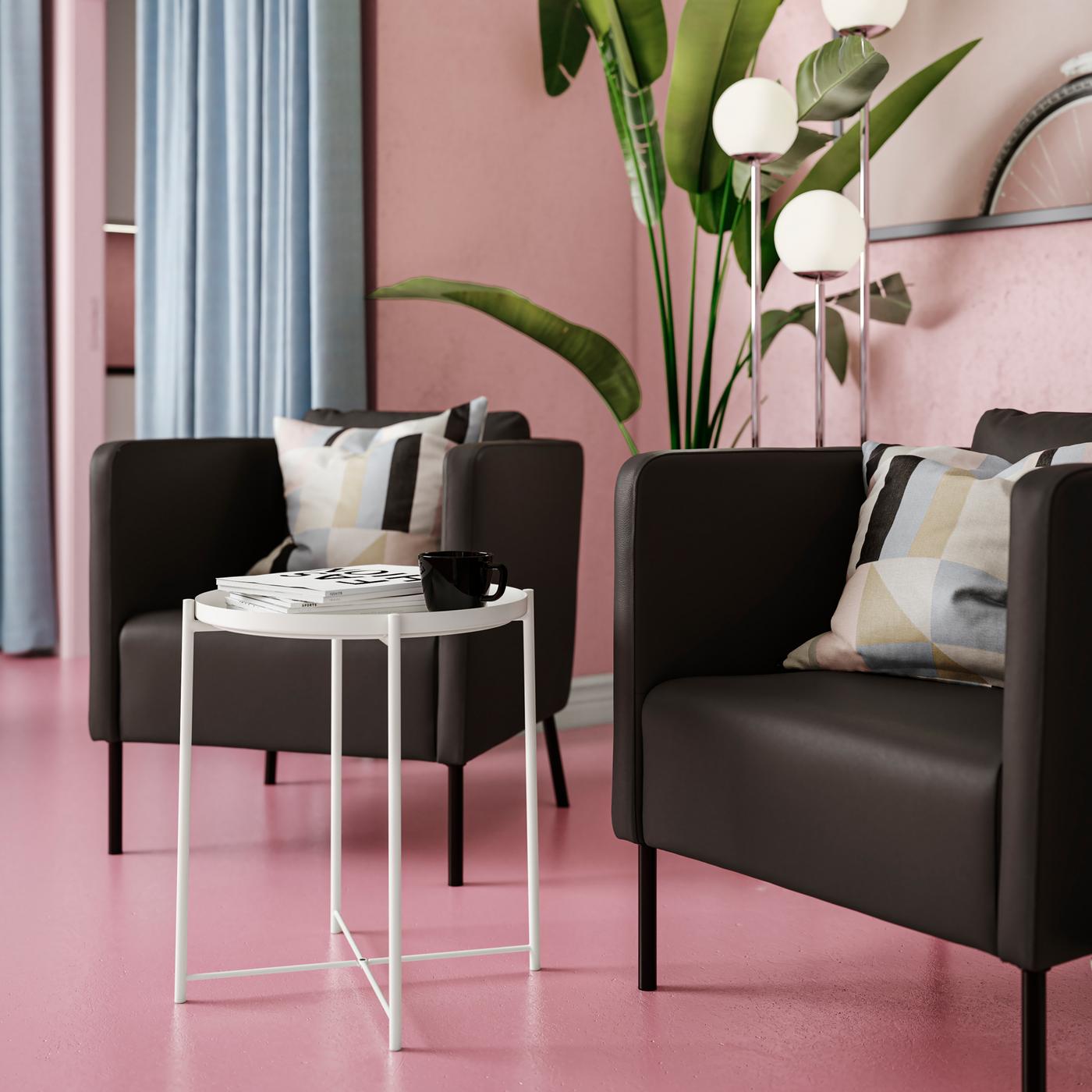 Due poltrone squadrate in stile moderno EKERÖ in similpelle nera accanto a un tavolino una stanza rosa - IKEA 