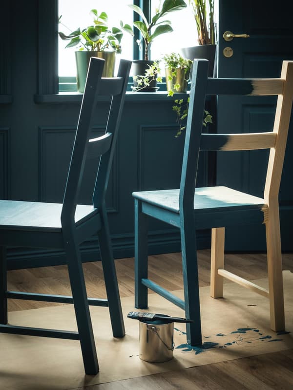 Due sedie che stanno venendo dipinte di verde  di cui una interamente e una a metà.