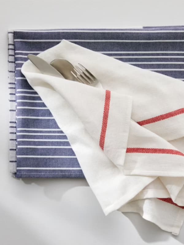 Due strofinacci da cucina. Uno a righe bianche e azzurre, l'altro bianco con riga rossa con all'interno delle posate.
