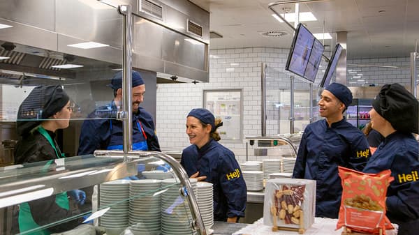 Dues col·laboradores d'IKEA, vestides amb uniformes del personal d'IKEA, gaudeixen d'un cafè juntes a la cantina.