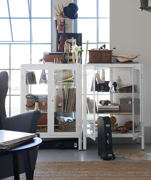 Dues vitrines IKEA FABRIKÖR juntes que mostren una col·lecció de records en una sala.