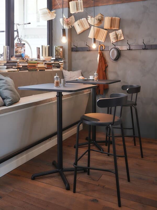 Dunkle Tische und Stühle an einer langen Sitzbank in einem Café.