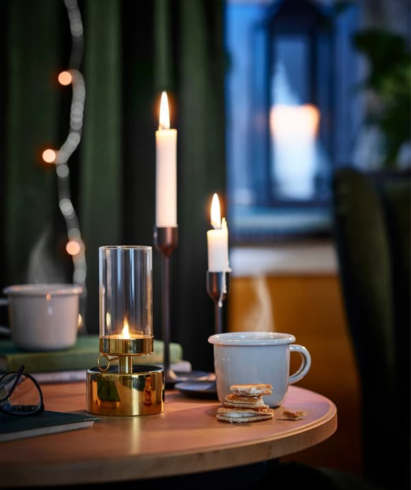 Durable, enamelled steel IKEA EGENDOM mug on a table with candlesticks.