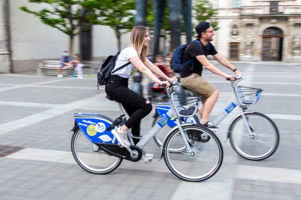Dva cyklisté přecházejí ulici.
