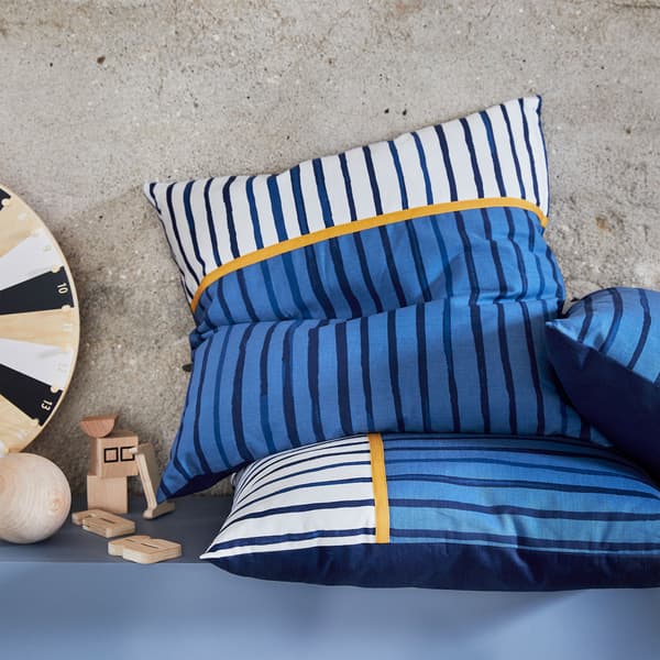 Dva polštáře SÅNGLÄRKA na sobě, námořnická modrá na jedné straně, na druhé straně modré, bílé a oranžové pruhy