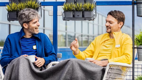 Dvaja zamestnanci IKEA sedia v kreslách pri káve a rozprávajú sa.