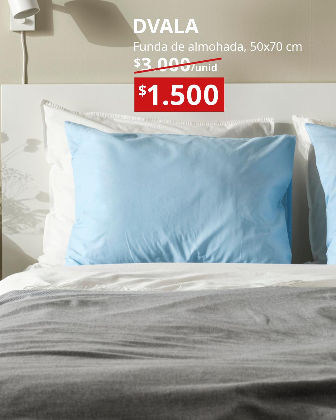 DVALA funda de almohada celeste 50x70 cm sobre cama con sábanas blancas y manta gris