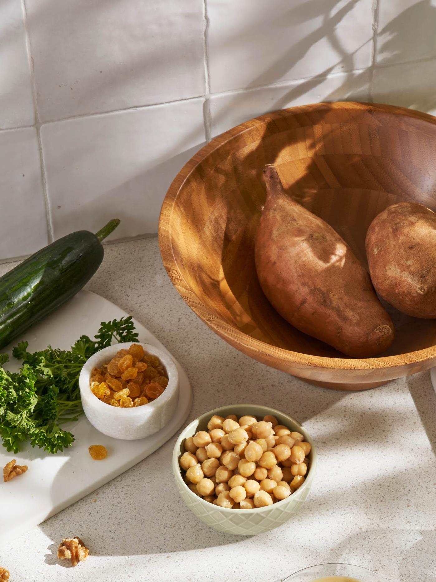 Dve bataty v bambusovej miske GRÖNSAKER, miska cícera, miska hrozienok a šalátová uhorka.