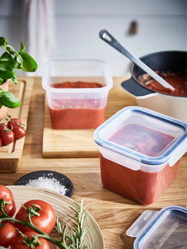 Dve čtvercové dózy IKEA 365+ 1,4 l plné paradajkového pyré stoja na drevenej pracovnej doske.
