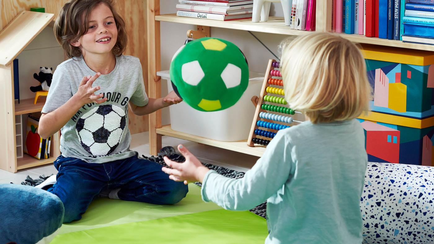 Dve deti si v rohu detskej izby hádžu zelenou loptou SPARKA.