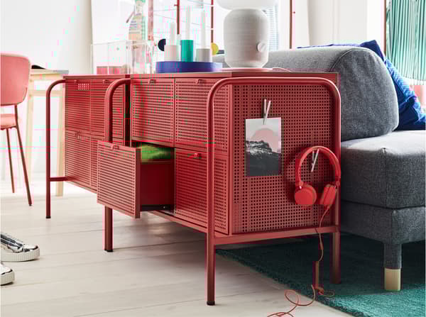 Dve IKEA NIKKEBY komode u crvenoj boji, s perforiranim površinama. Postavljene su iza sofe na razvlačenje u spavaćoj sobi.