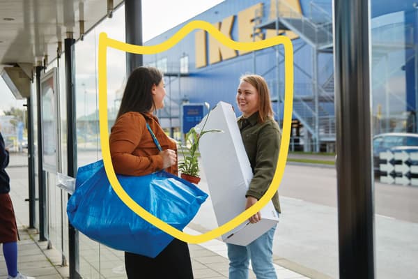Dve osebi prek trgovino IKEA z nakupljenimi izdelki.