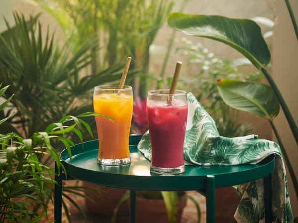 Dvě sklenice se smoothie FRUKSTUND postavené na stolku obklopeném květinami