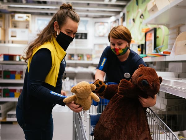 Dvě zaměstnankyně IKEA dávají plyšové medvídky do košíku.