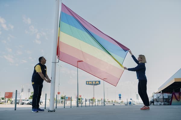 Dvoje ljudi podižu dugu zastavu ispred IKEA trgovine.