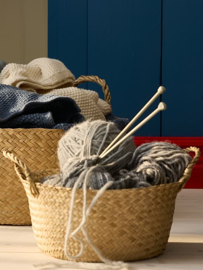 Dwa kosze wypełnione włóczką i kijkami do robienia na drutach.