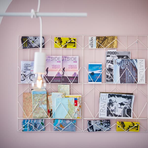Dwie białe tablice na notatki KVICKSUND zawieszone na różowej ścianie. Poukładano na nich przewodniki turystyczne, mapy i czasopisma podróżnicze.