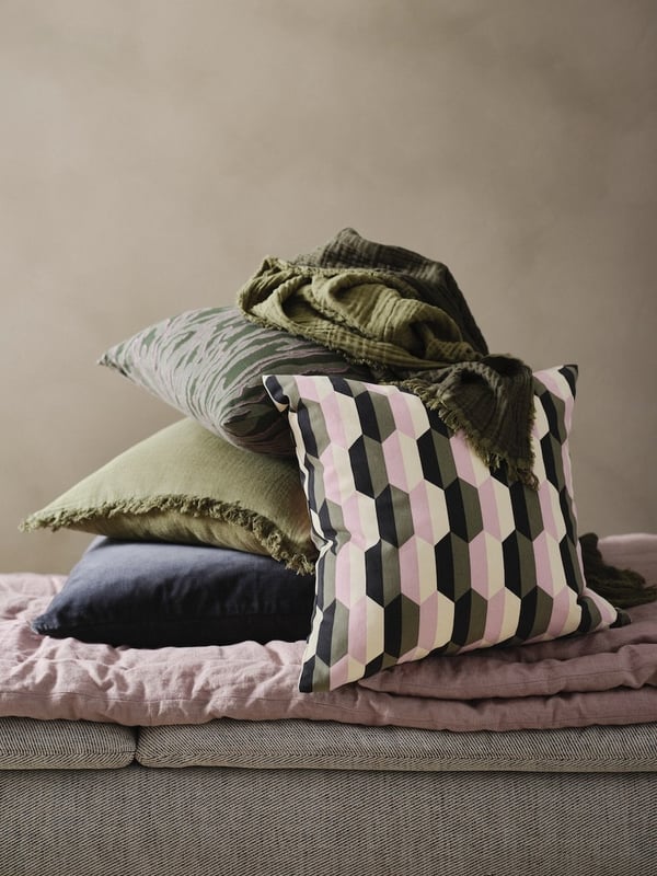 Dwie poduszki GULDFLY, jedna antracytowa ze wzorem w kolorze złamanej bieli, a druga w kolorze złamanej bieli z żółto-beżowym wzorem.